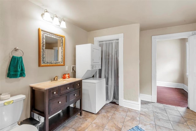 bathroom featuring tile patterned flooring, vanity, stacked washing maching and dryer, and toilet