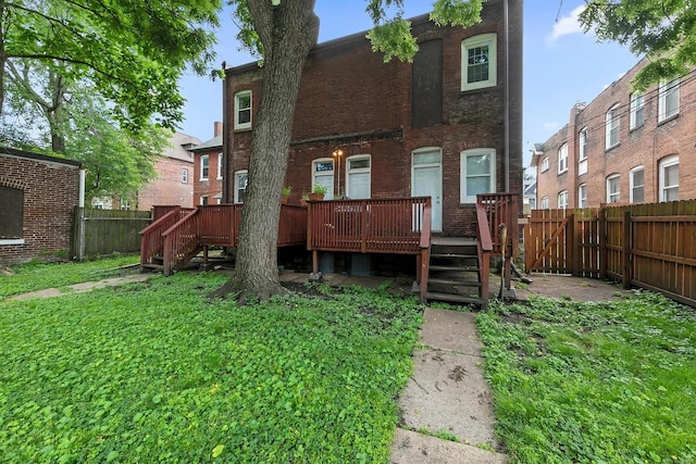 rear view of house with a lawn and a wooden deck