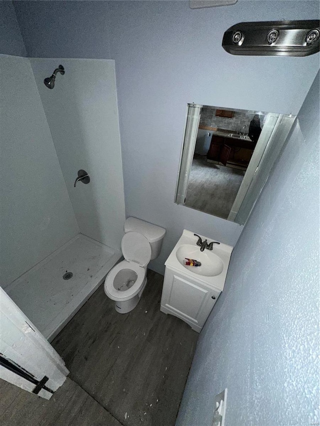 bathroom featuring hardwood / wood-style floors, vanity, toilet, and a shower