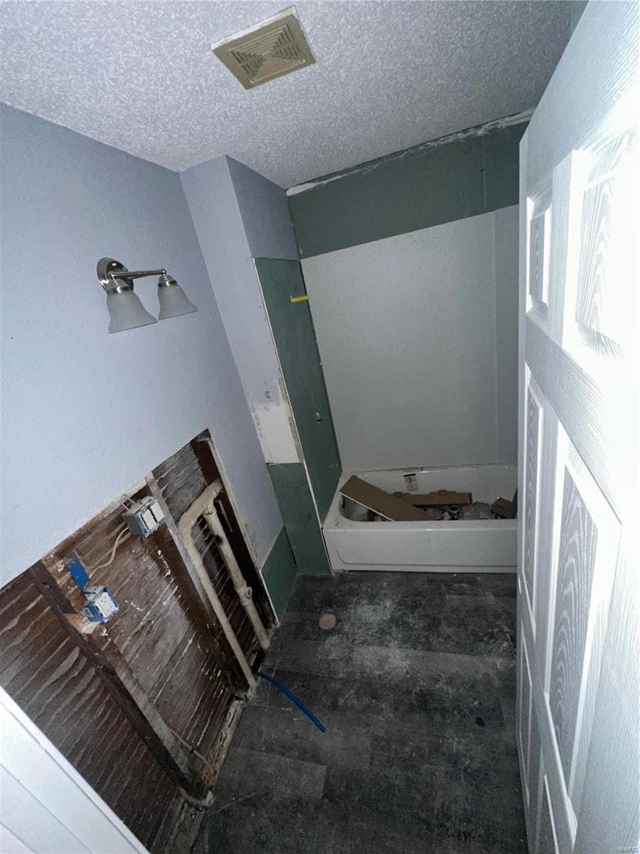 bathroom with a textured ceiling and a tub