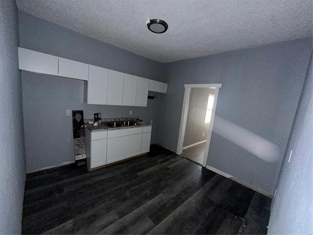 kitchen featuring white cabinets, sink, dark hardwood / wood-style flooring, and a textured ceiling