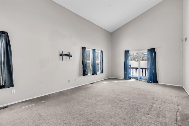 carpeted spare room with high vaulted ceiling