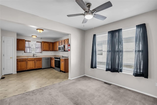 kitchen featuring ceiling fan, light colored carpet, sink, and appliances with stainless steel finishes