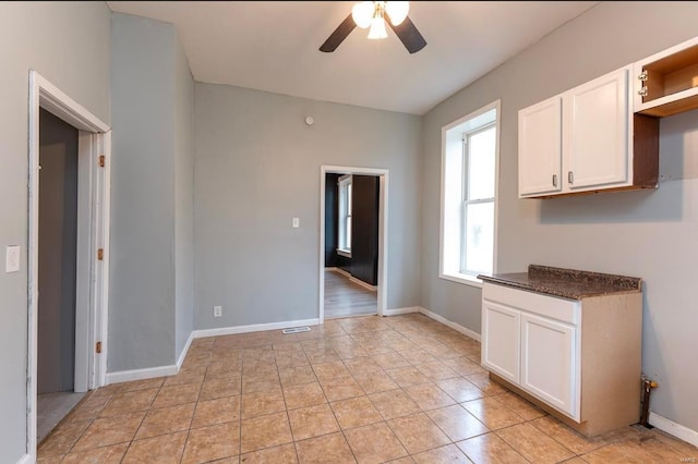 interior space with light tile patterned floors, white cabinetry, and ceiling fan