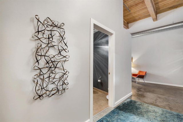 hallway with beamed ceiling, wood ceiling, and concrete flooring