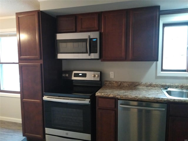 kitchen with hardwood / wood-style floors, sink, crown molding, and stainless steel appliances