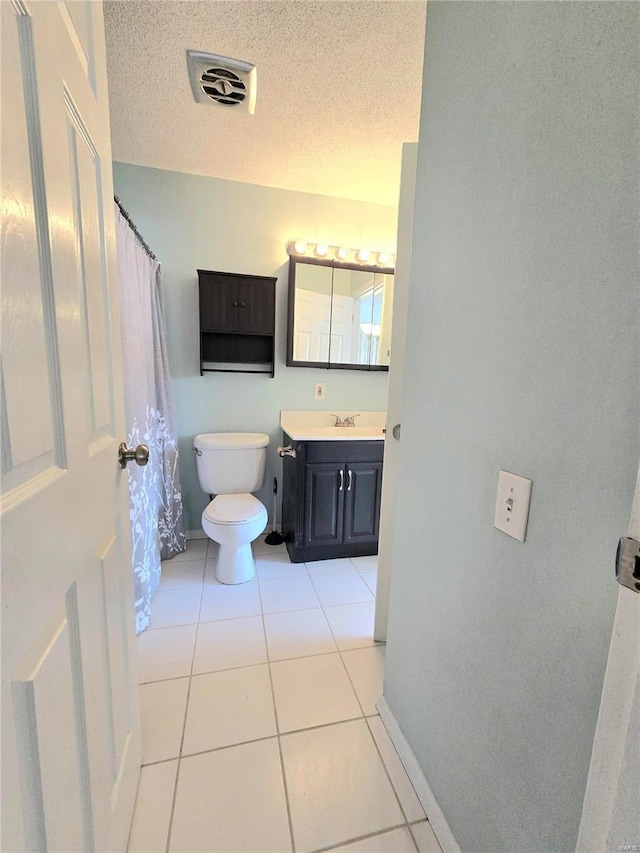 bathroom featuring tile patterned flooring, vanity, a textured ceiling, and toilet