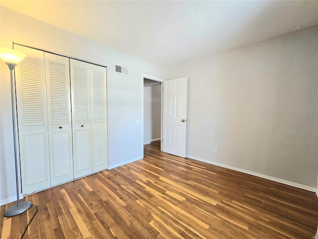 unfurnished bedroom with dark hardwood / wood-style floors and a closet