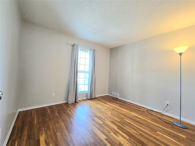 spare room with dark hardwood / wood-style flooring and a textured ceiling