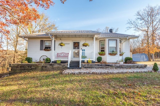 view of front of home featuring a storage unit, a porch, and a front lawn