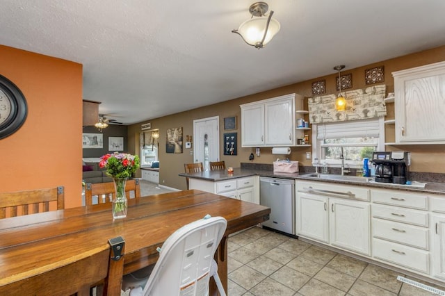 kitchen with kitchen peninsula, sink, decorative light fixtures, dishwasher, and white cabinetry