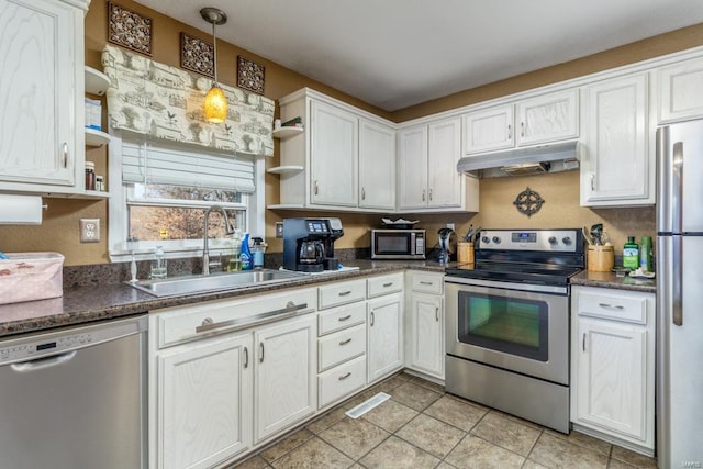 kitchen featuring white cabinets, sink, light tile patterned floors, appliances with stainless steel finishes, and decorative light fixtures