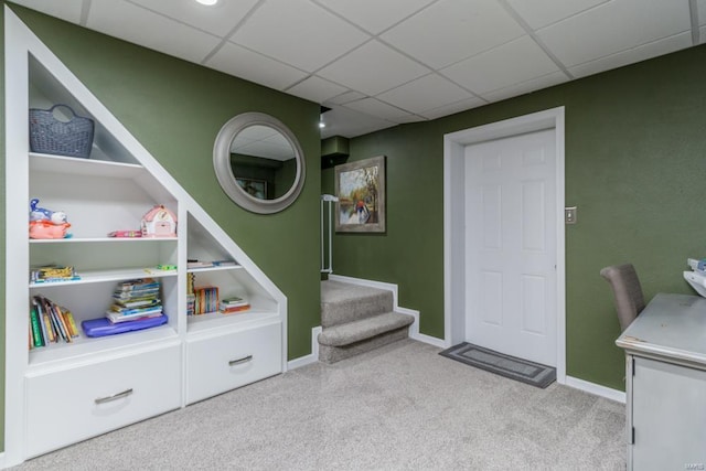 rec room with built in shelves and light carpet