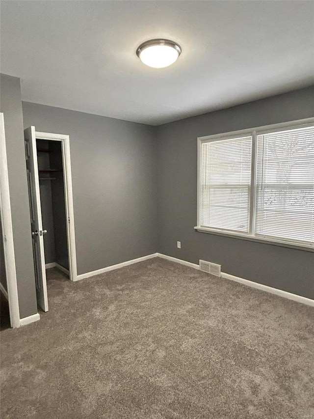 unfurnished bedroom featuring dark colored carpet and a closet