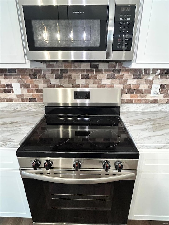 interior details with white cabinets, appliances with stainless steel finishes, backsplash, and light stone counters