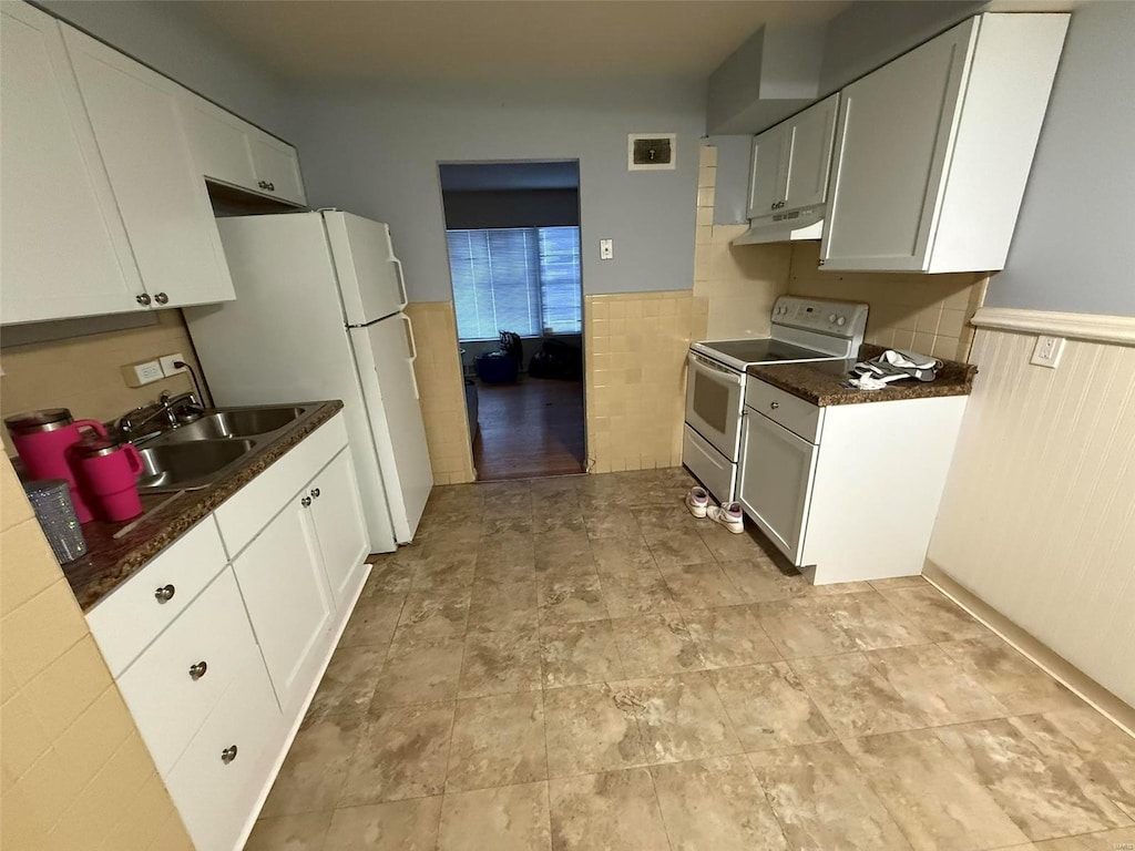 kitchen with white cabinetry, sink, dark stone counters, and white appliances