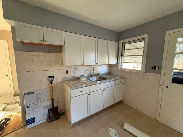 kitchen featuring light tile patterned floors, white cabinetry, tile walls, and sink