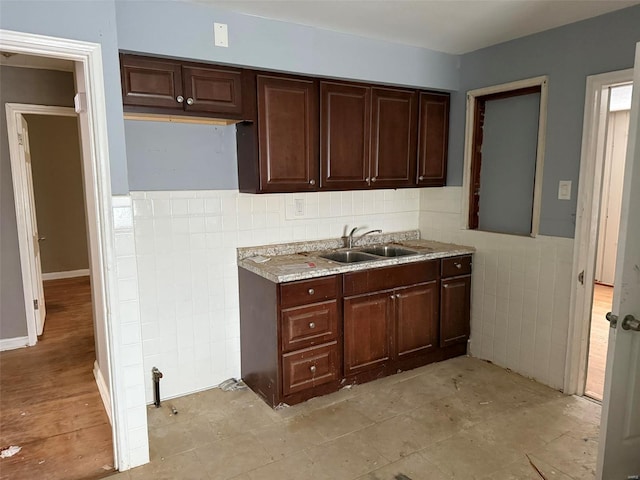 kitchen with dark brown cabinetry, tile walls, and sink