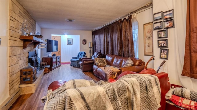 living room with hardwood / wood-style floors, a textured ceiling, and a baseboard heating unit