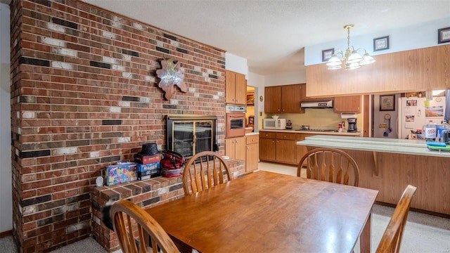 dining room featuring a chandelier, a textured ceiling, a fireplace, and brick wall