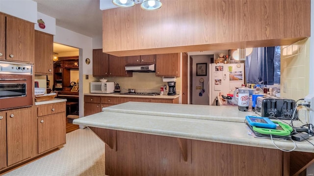 kitchen with decorative backsplash, white appliances, kitchen peninsula, and a breakfast bar area