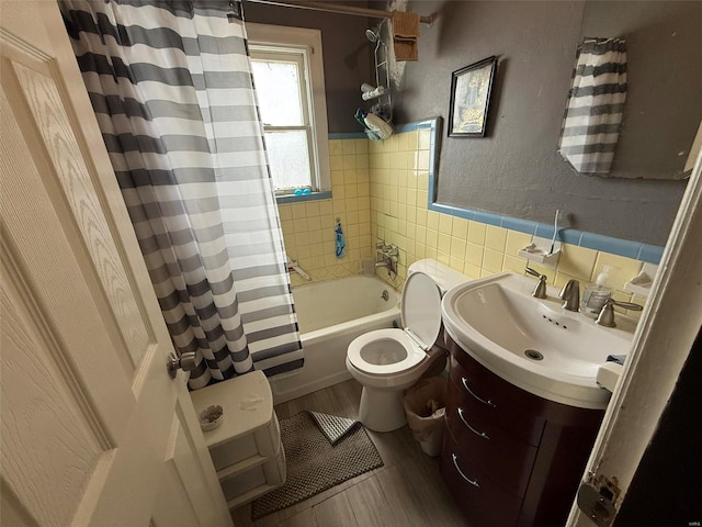 full bathroom with hardwood / wood-style floors, vanity, toilet, tile walls, and shower / tub combo with curtain