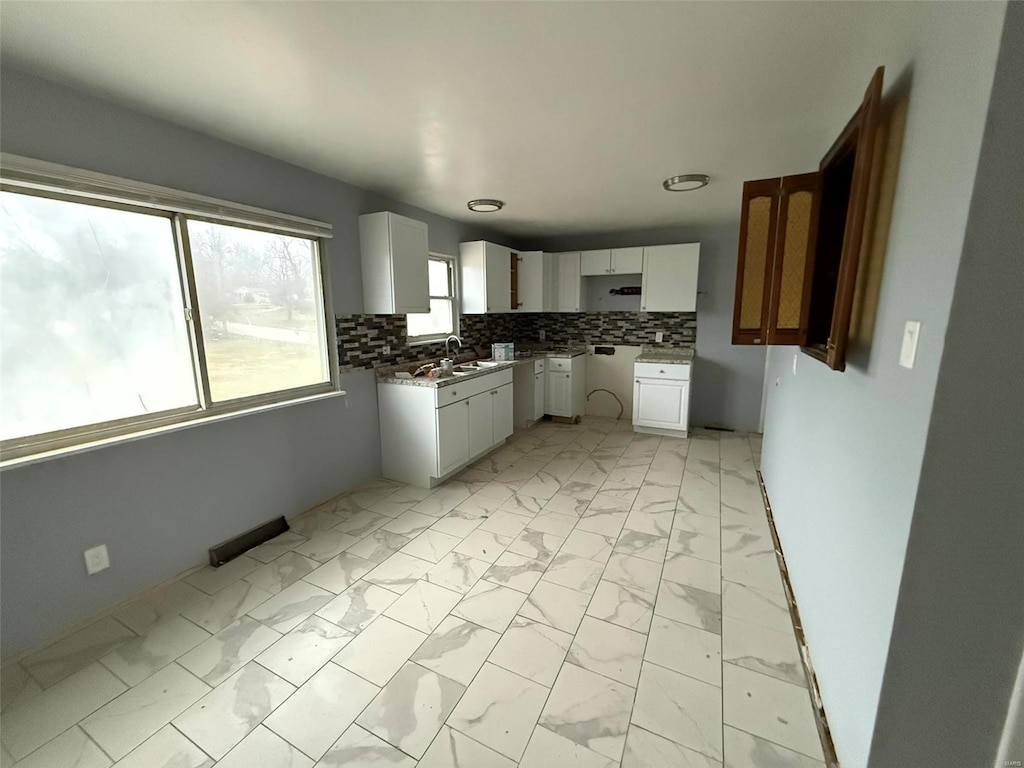 kitchen with decorative backsplash, white cabinetry, and sink