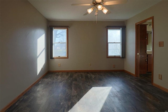 spare room featuring dark wood-type flooring, ceiling fan, and a healthy amount of sunlight