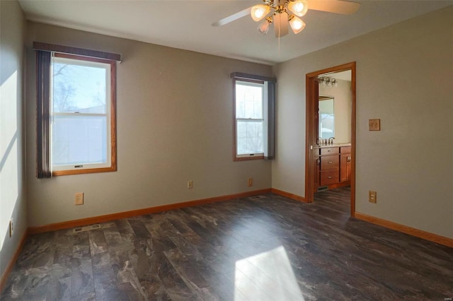 empty room with dark hardwood / wood-style floors, ceiling fan, and a healthy amount of sunlight