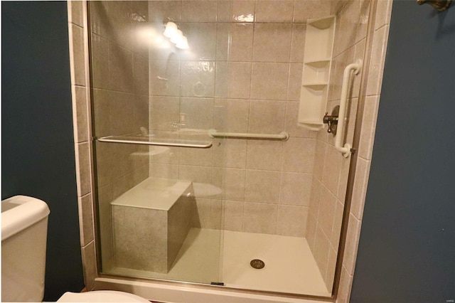 bathroom featuring toilet and a shower with shower door