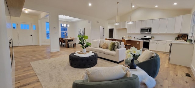 living room featuring high vaulted ceiling, sink, and light hardwood / wood-style floors