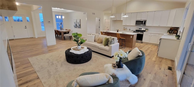 living room featuring lofted ceiling, sink, and light wood-type flooring