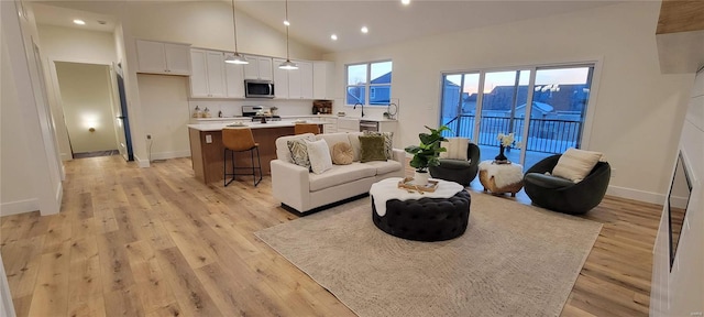 living room with high vaulted ceiling and light hardwood / wood-style flooring