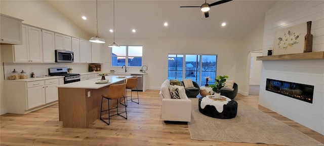 kitchen with a kitchen island, decorative light fixtures, a breakfast bar area, white cabinets, and stainless steel appliances