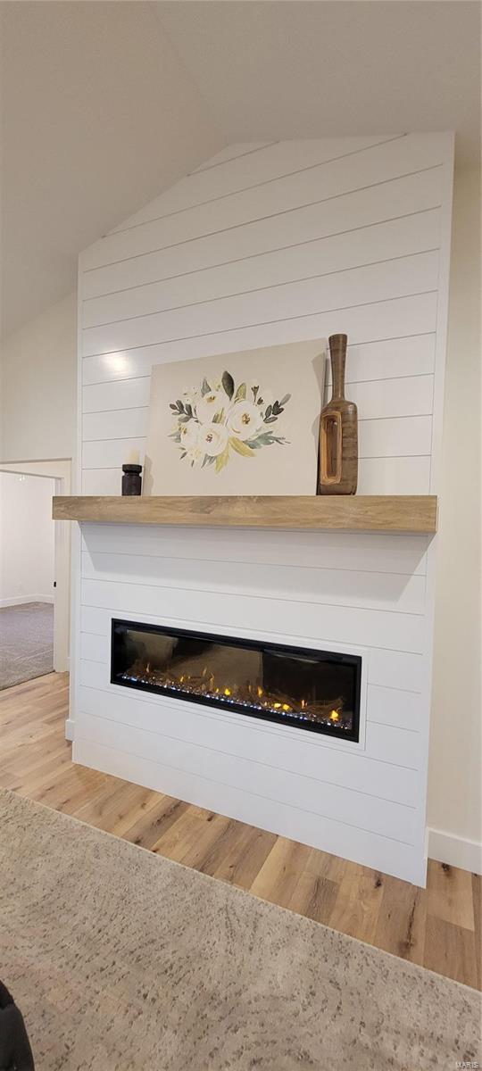 room details with hardwood / wood-style floors and a large fireplace