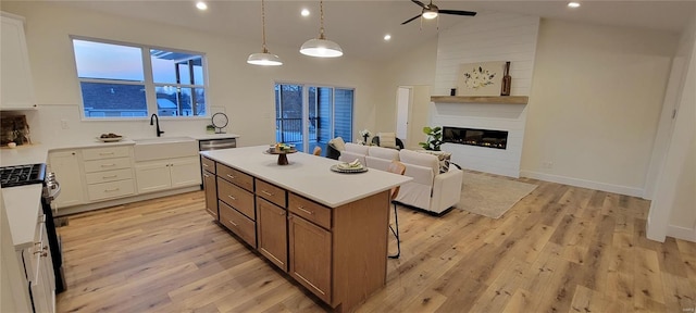 kitchen featuring stainless steel appliances, white cabinetry, a center island, and decorative light fixtures