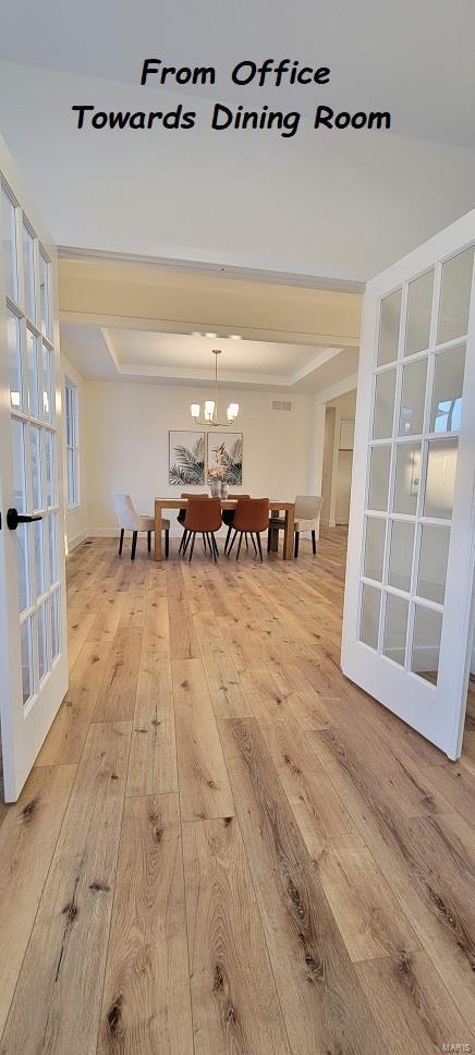 dining space featuring french doors, wood-type flooring, and a tray ceiling