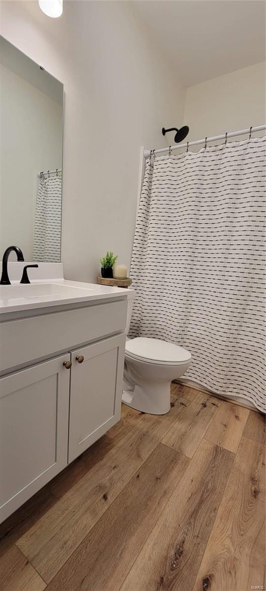 bathroom featuring vanity, curtained shower, wood-type flooring, and toilet