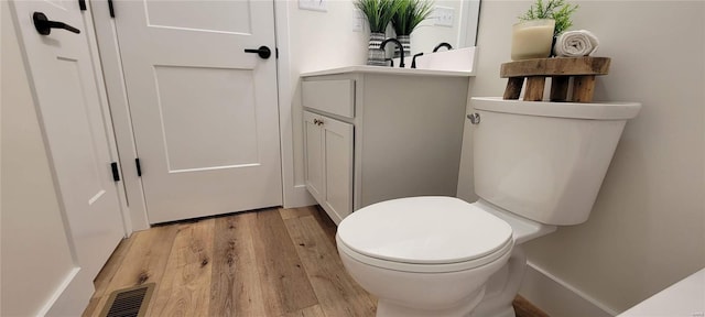 bathroom with hardwood / wood-style flooring, vanity, and toilet