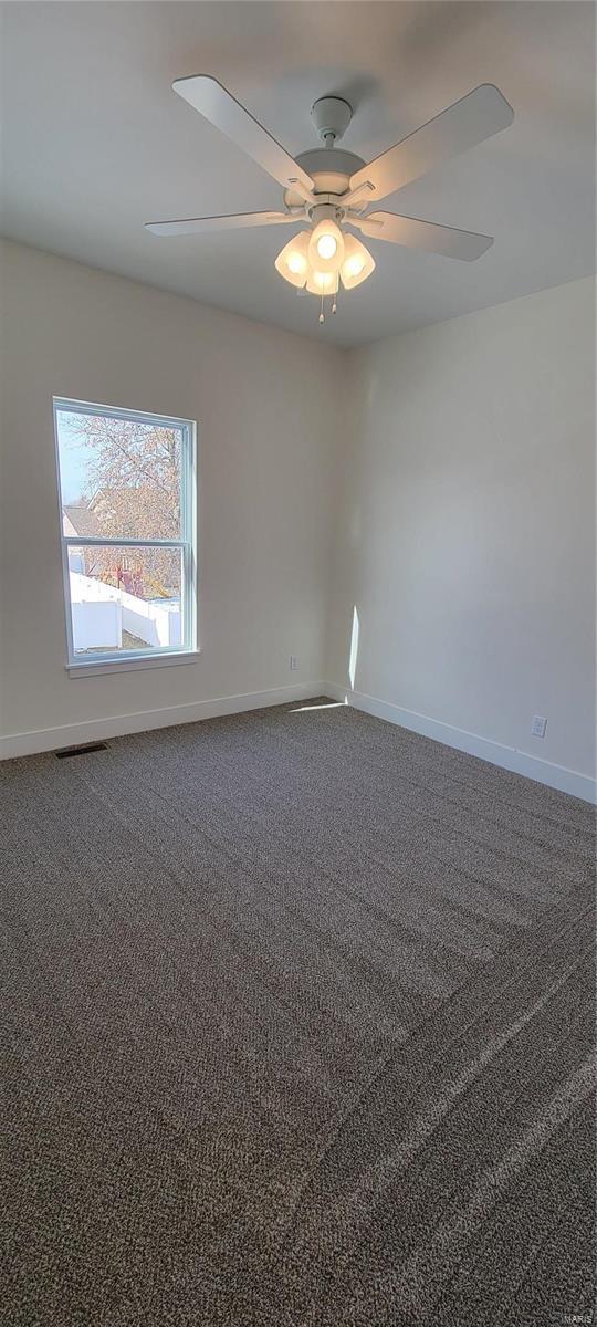 empty room featuring ceiling fan and carpet