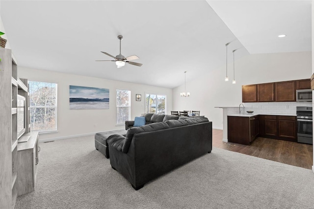 living room featuring lofted ceiling, dark carpet, and ceiling fan with notable chandelier