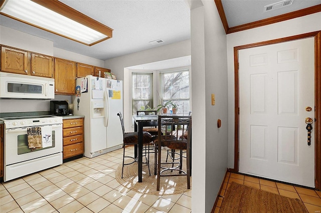 kitchen with a textured ceiling, light tile patterned flooring, ornamental molding, and white appliances