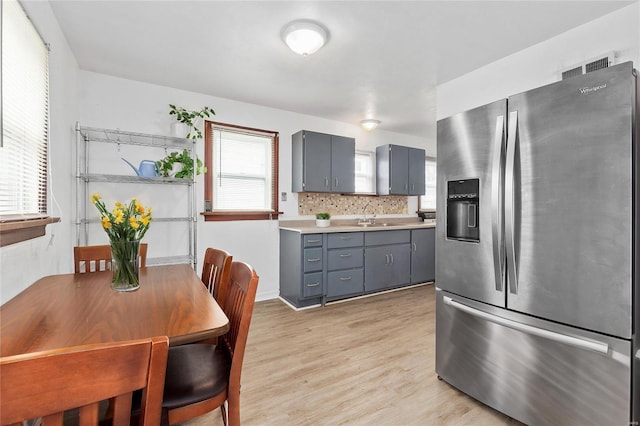 kitchen with stainless steel refrigerator with ice dispenser, tasteful backsplash, plenty of natural light, and sink