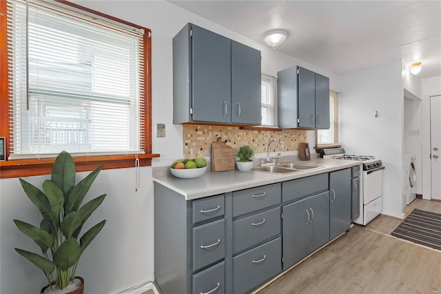 kitchen with a healthy amount of sunlight, white range, sink, tasteful backsplash, and light hardwood / wood-style floors