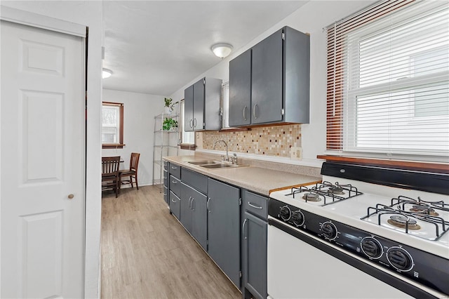 kitchen with gray cabinetry, backsplash, gas range gas stove, and sink