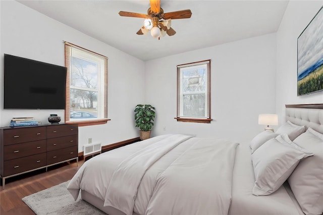 bedroom featuring ceiling fan, dark wood-type flooring, and multiple windows