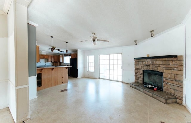 living room featuring a textured ceiling, ceiling fan, ornamental molding, and a fireplace