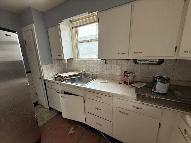 kitchen featuring white cabinets, stainless steel fridge, tasteful backsplash, and sink