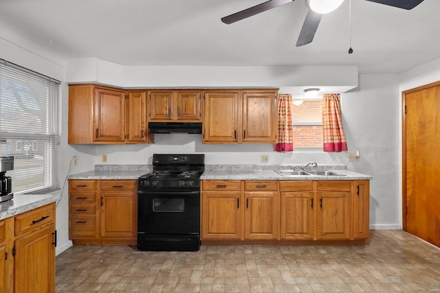 kitchen featuring ceiling fan, light stone countertops, sink, and black gas range oven