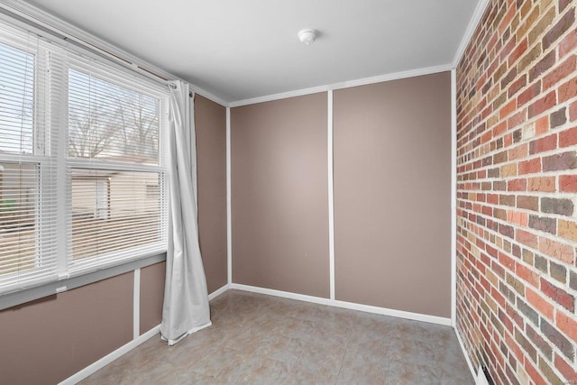 spare room with crown molding and brick wall